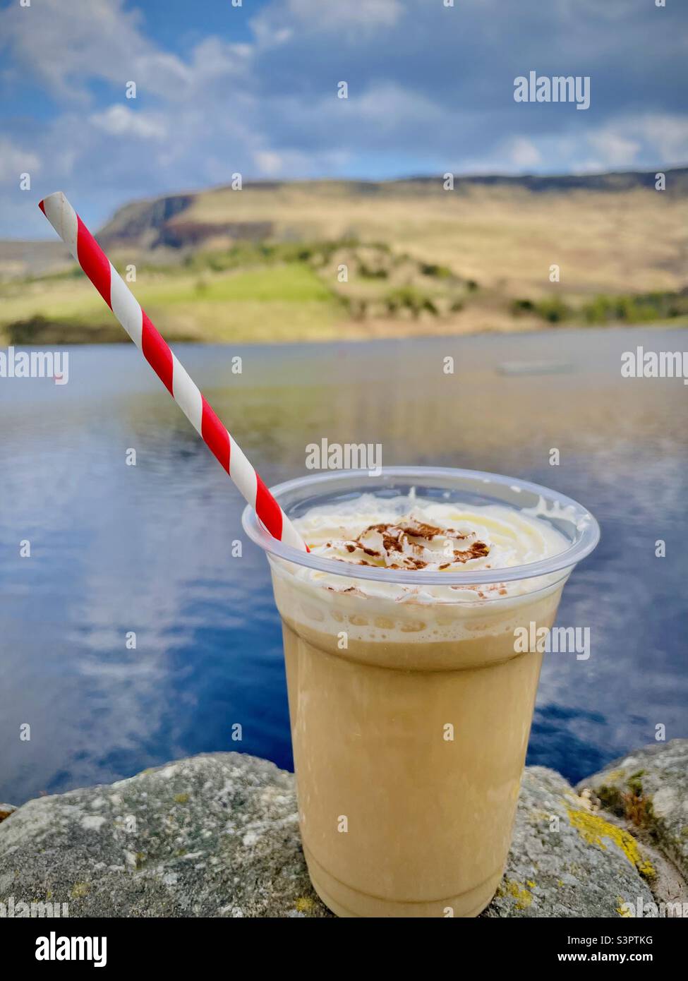 Caffè ghiacciato con panna con una paglia a strisce con una bella vista panoramica sullo sfondo Foto Stock