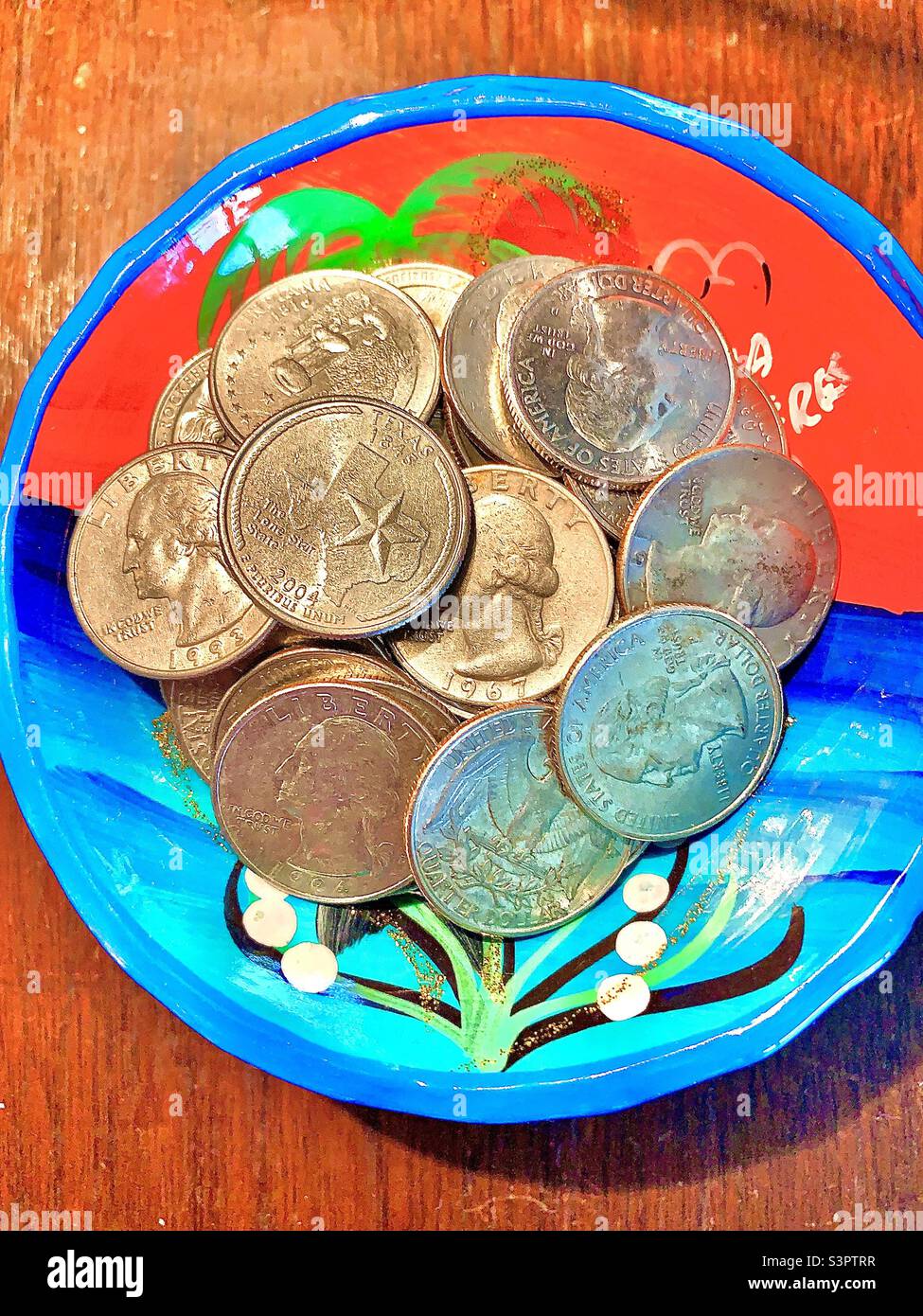 Raccolta di quarti in vaso colorato sono centrati su tavolo di legno Foto Stock
