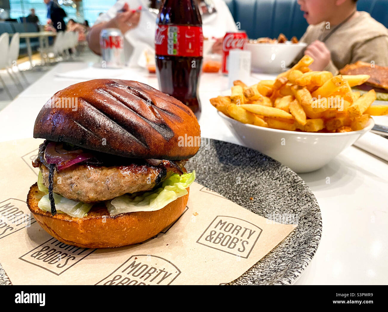 Hamburger, patatine e una bottiglia di Coca-Cola acquistati presso un'area ristoro di Londra. Foto Stock