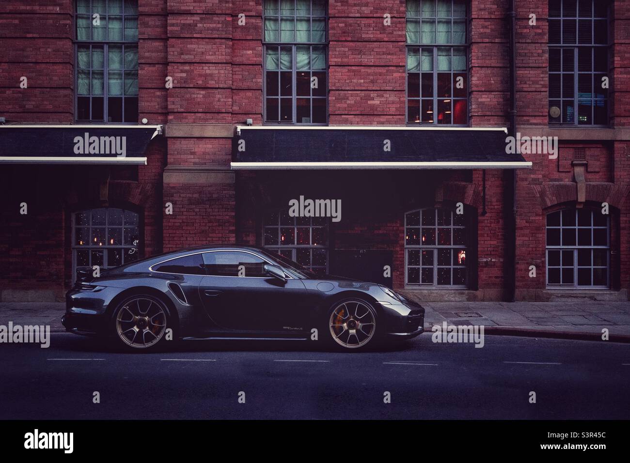 Supercar sport auto Porsche coupé parcheggiato all'esterno di un lussuoso magazzino appartamento - Immagine stock catturata con smartphone