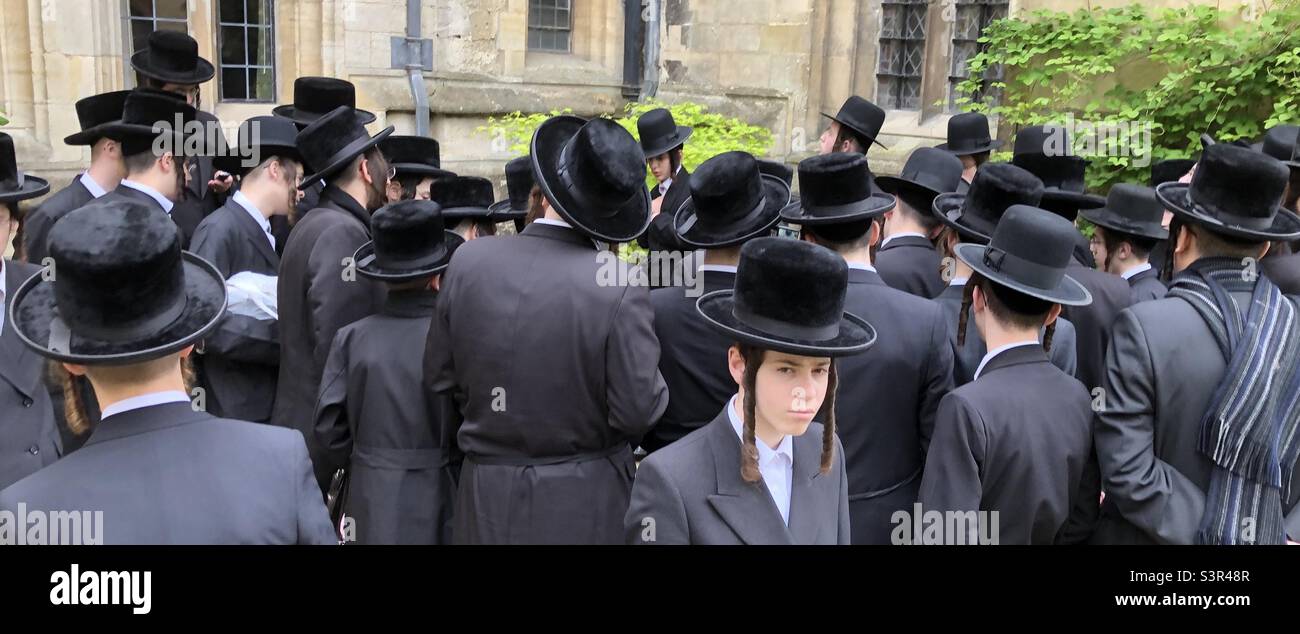 Un gruppo di ebrei ultra-ortodossi che pregano all'aria aperta accanto a un monumento commemorativo in una tomba medievale a Oxford. Foto Stock