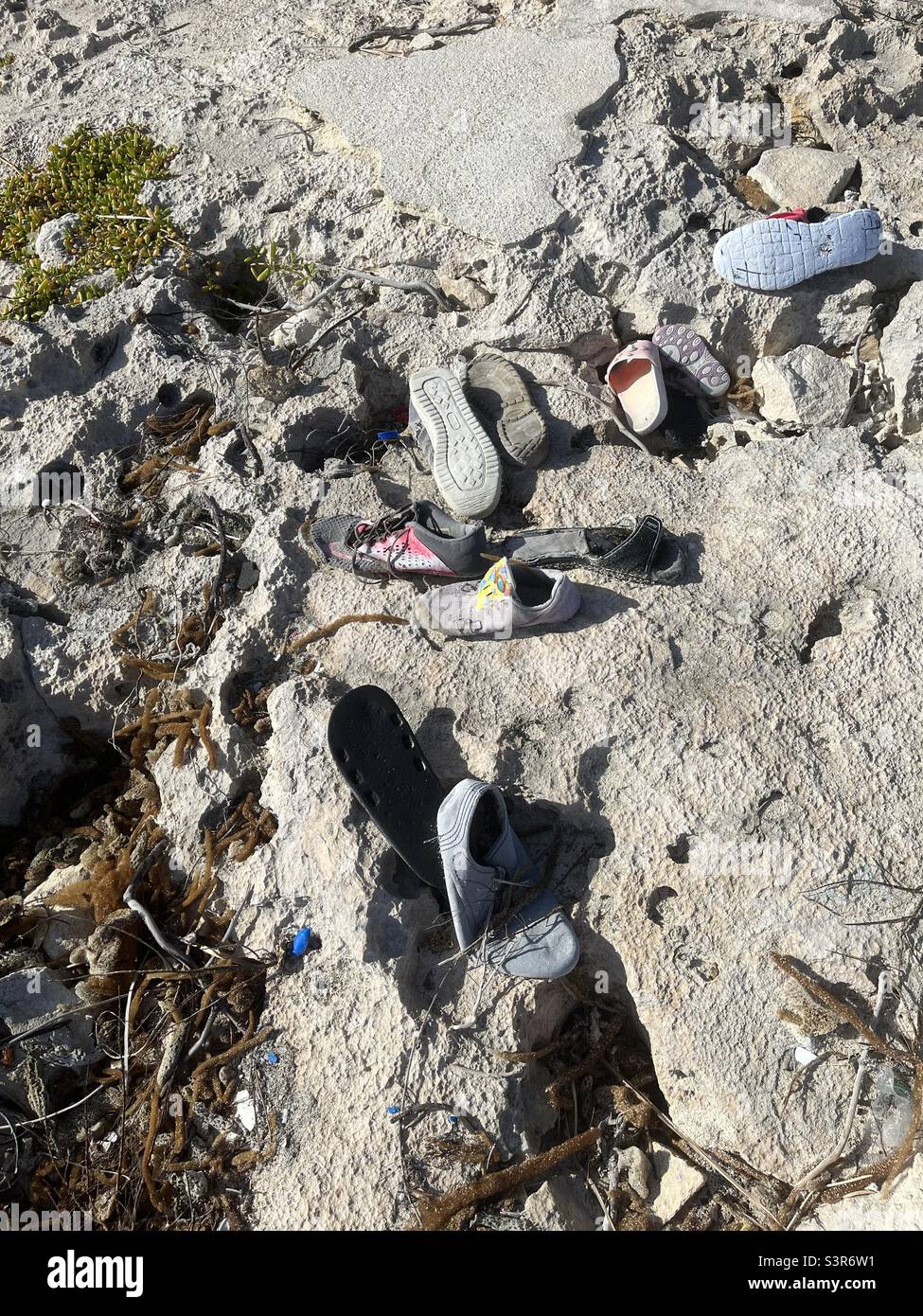 Le scarpe scartate sono state lavate sulla spiaggia Foto Stock