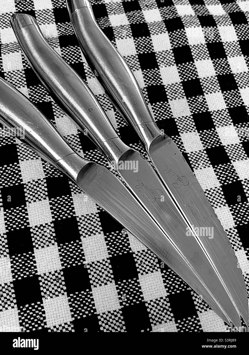 Tre coltelli a bistecca su sfondo bianco e nero Gingham - Immagine stock catturata con smartphone