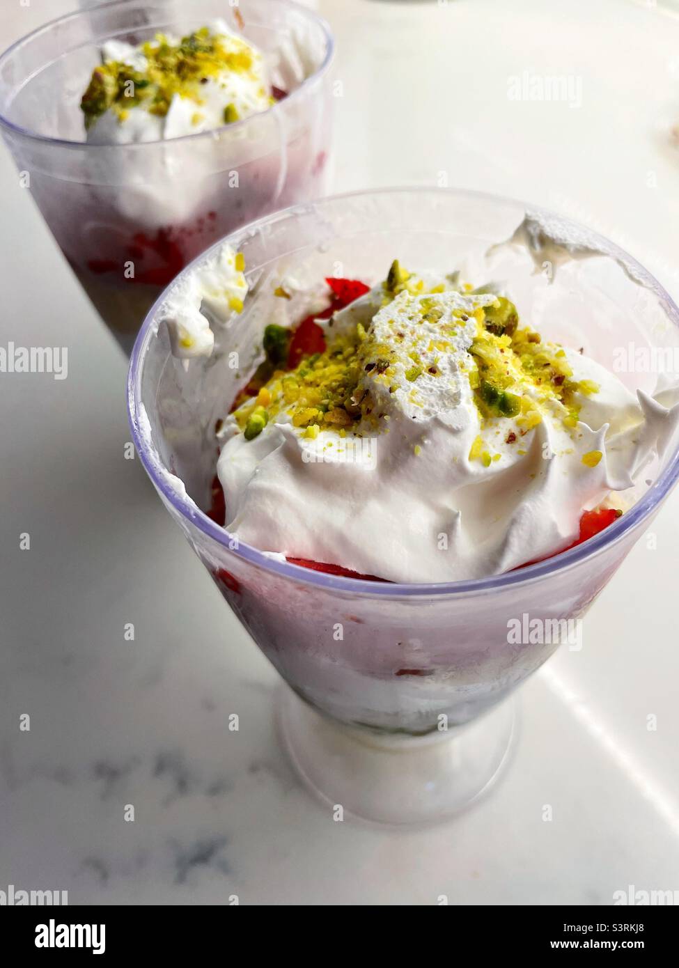 Due bicchieri da parfait riempiti di frutta montata con panna sopra fanno un dessert elegante, 2022, Stati Uniti - Immagine stock catturata con smartphone