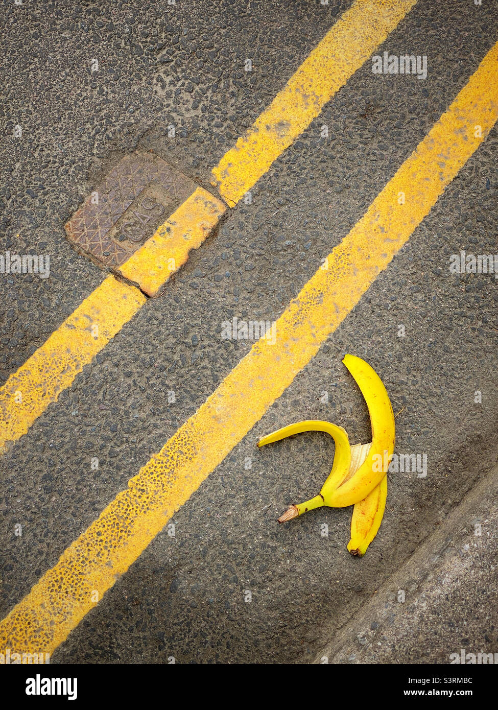 Fare attenzione al pericolo di inciampo - una buccia/buccia di banana scartata sul lato di una strada potrebbe essere letale. Linee gialle doppie - nessun parcheggio in qualsiasi momento. Foto ©️ COLIN HOSKINS. Foto Stock