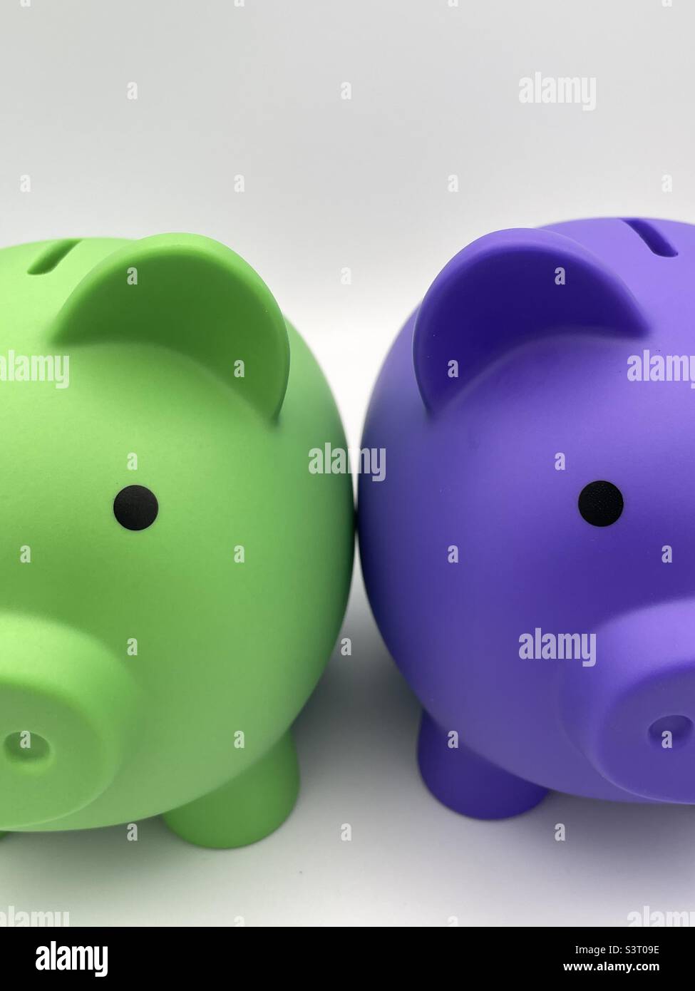 Due banchi di piggy per bambini di colore diverso, viola e verde lime, seduti fianco a fianco. Foto Stock