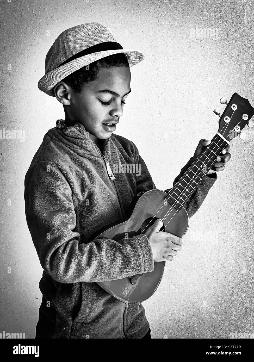 Ragazzo giovane in cappello che gioca ukulele Foto Stock