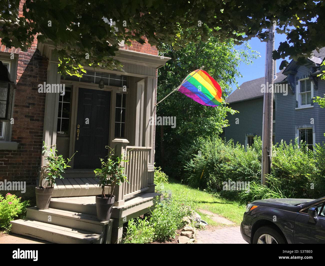 Bandiera orgoglio esposto con orgoglio fuori di una bella casa, ondeggiare nella brezza, Ontario, Canada. Una casa di famiglia gay in un bel quartiere. Foto Stock