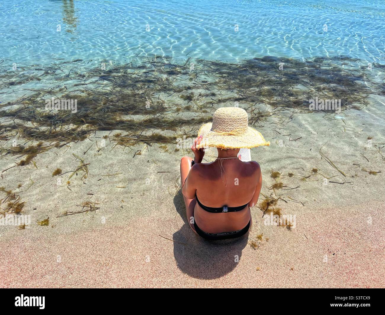 Donna che legge un libro sulla spiaggia Elafonisi Creta Grecia Foto Stock