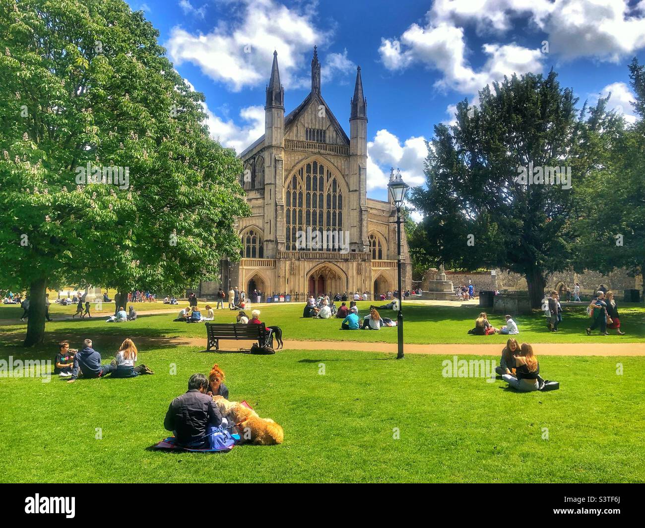 Persone che godono del sole primaverile nella Winchester Cathedral Grounds, Regno Unito Foto Stock