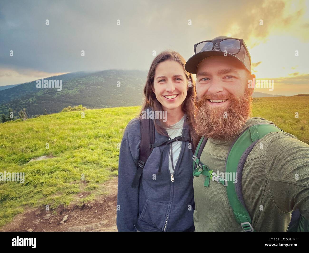 Un uomo e una donna prendono un selfie al tramonto su un sentiero escursionistico Foto Stock