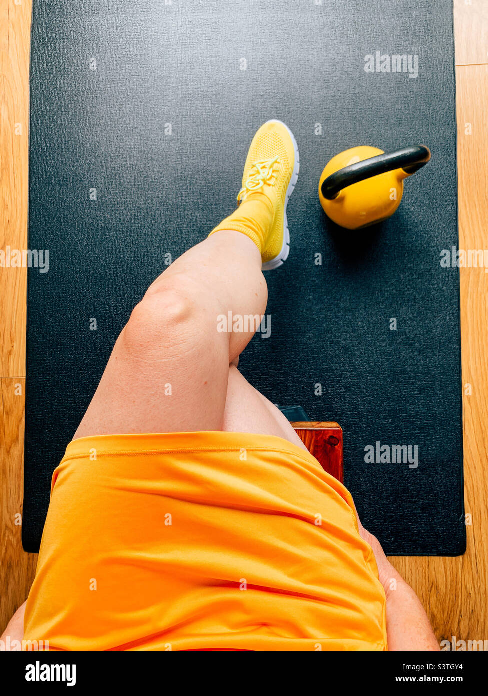 Donna che indossa il giallo in palestra accanto a un peso Kettlebell Foto Stock