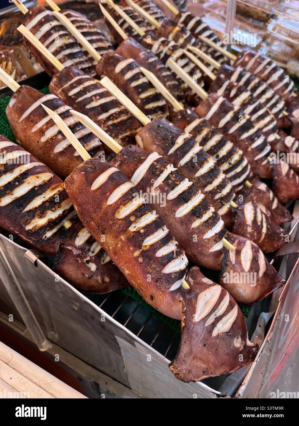 Cibo di strada giapponese - ika yaki - calamari alla griglia su un bastone - Immagine stock catturata con smartphone