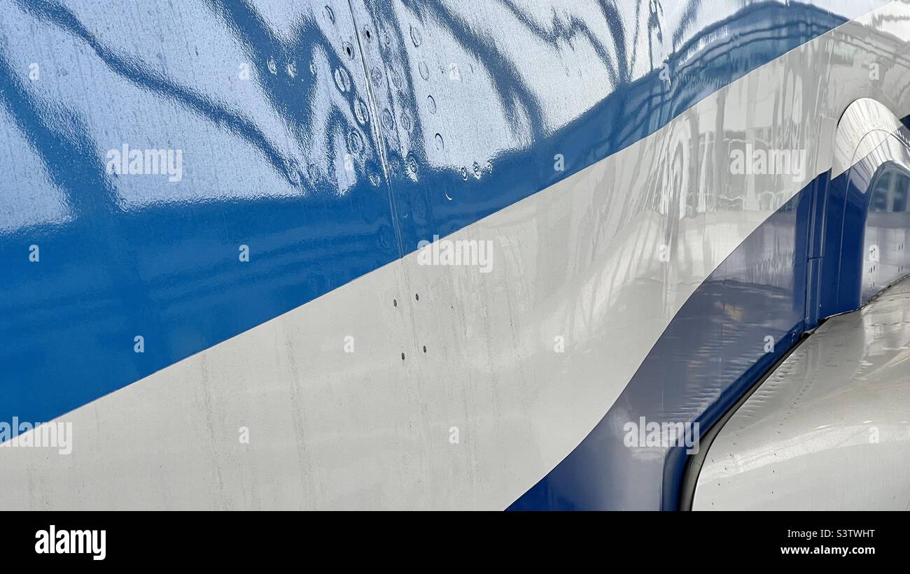 Dettaglio della fusoliera del grande esterno del jet passeggero, con strisce blu chiare e scure su bianco. Adatto per lo sfondo per grafica e testo - Immagine stock catturata con smartphone