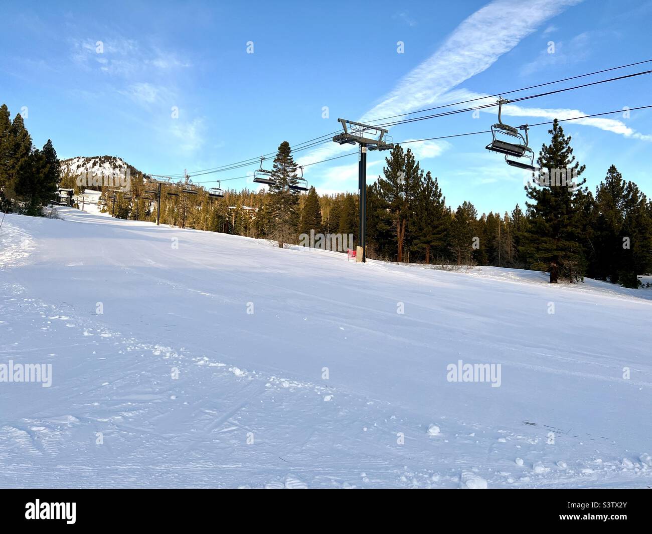 Seggiovie vuote sulle piste per principianti dell'area sciistica e snowboard di Mammoth Mountain, California. Cielo blu - Immagine stock catturata con smartphone