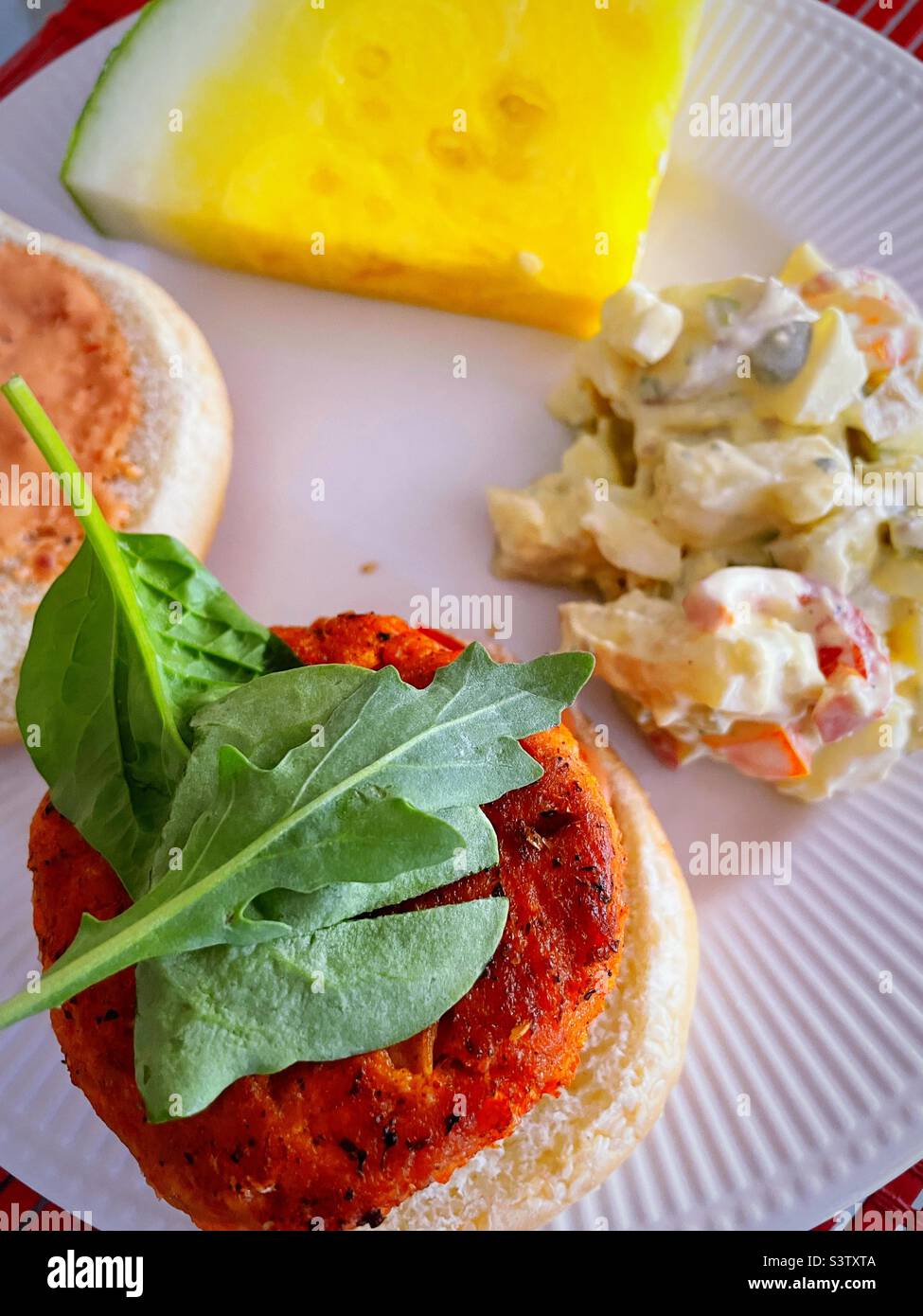 Primo piano di un pasto estivo di hamburger di salmone, melone giallo e insalata di patate fatta in casa, 2022, USA - Immagine stock catturata con smartphone
