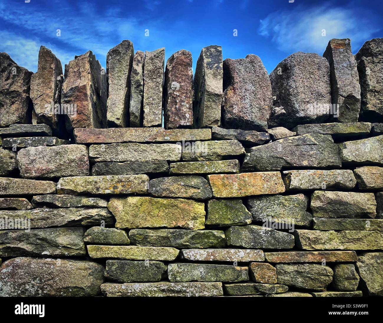 ‘Safe as houses’ un tradizionale muro di pietra a secco dello Yorkshire si erge fiero come il giorno della sua costruzione, completato dai cieli azzurri dell’estate Foto Stock