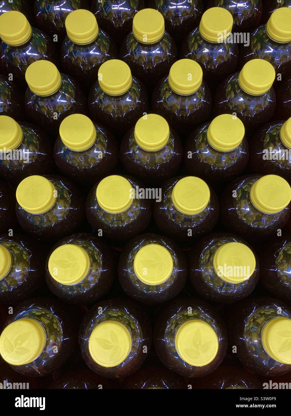 Bottiglie di plastica per bibite analcoliche con tappi gialli in fila dall'alto Foto Stock