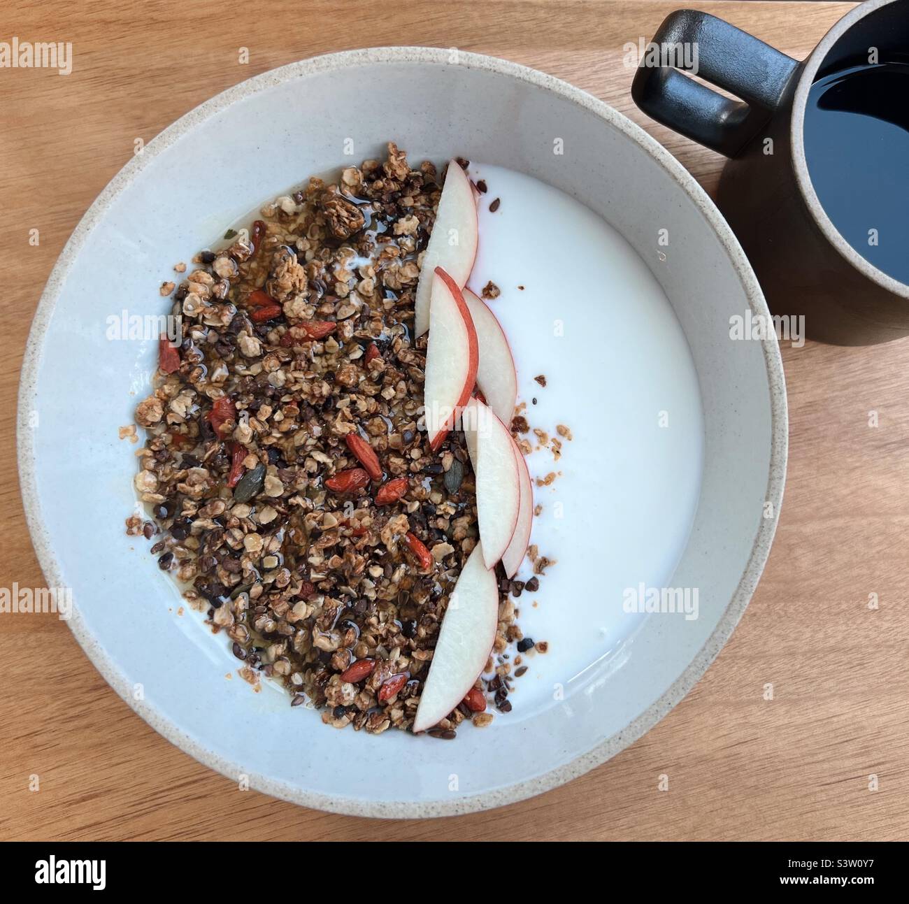 Muesli e yogurt con fette di mela e caffè nero Foto Stock