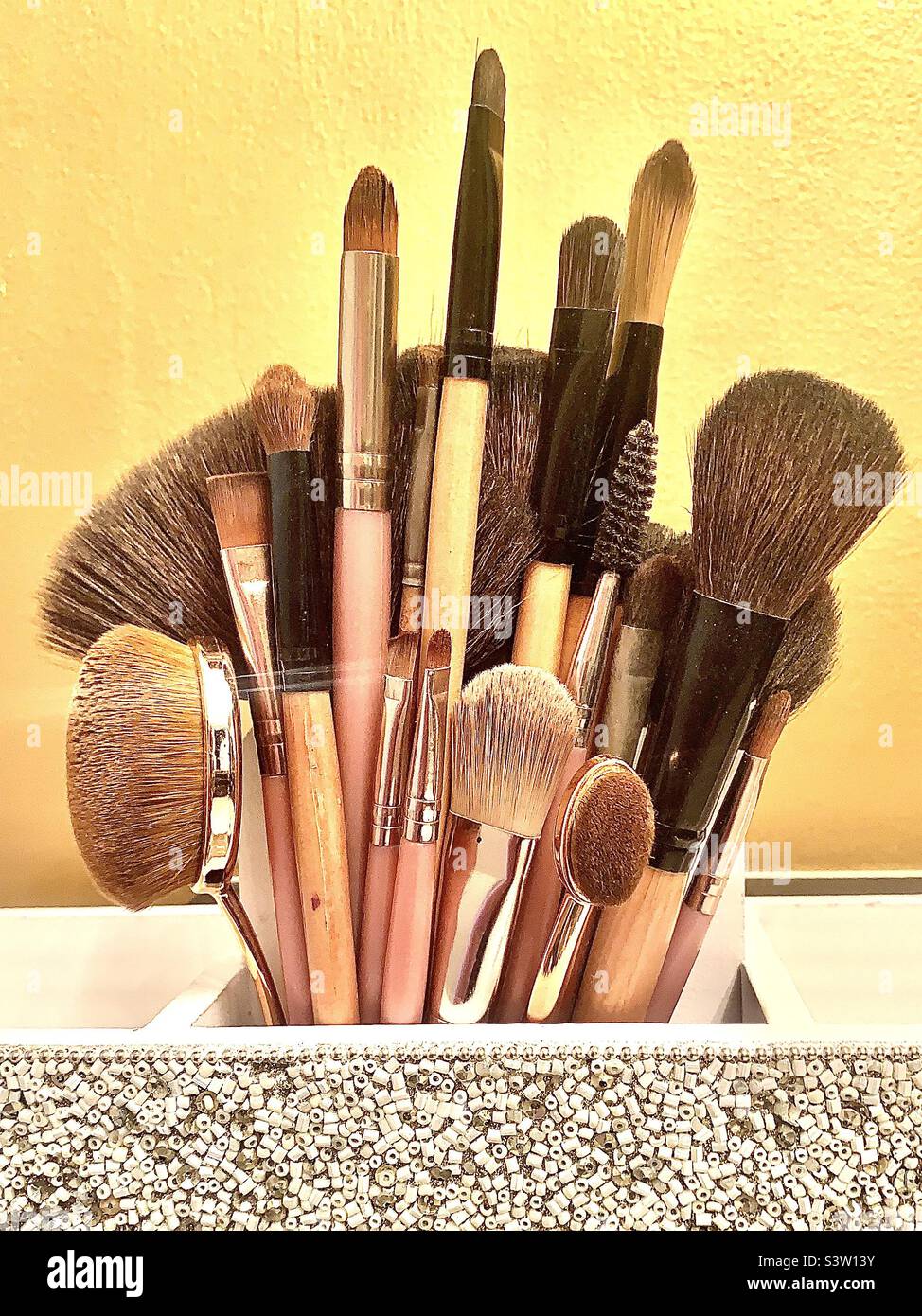 Selezione ordinata di pennelli da trucco su sfondo giallo con spazio di copia Foto Stock
