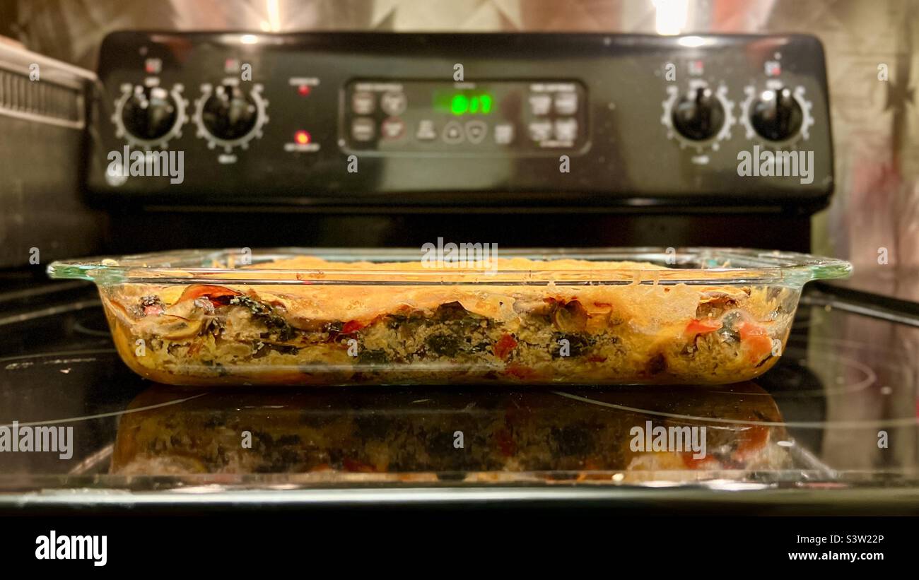 Lasagne vegane prive di frumento, senza glutine, fatte con fogli di patate dolci, tagliate a sostituzione della pasta, adagiata in casseruola su piano cottura - Immagine stock catturata con smartphone