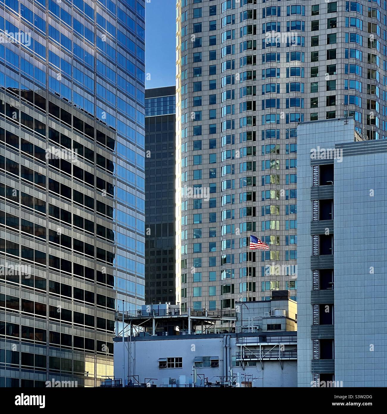 LOS ANGELES, CA, MAR 2022: L'albero della luce del sole illumina le stelle e le strisce, la bandiera degli Stati Uniti che vola tra grattacieli nel distretto finanziario del centro - Immagine stock catturata con smartphone