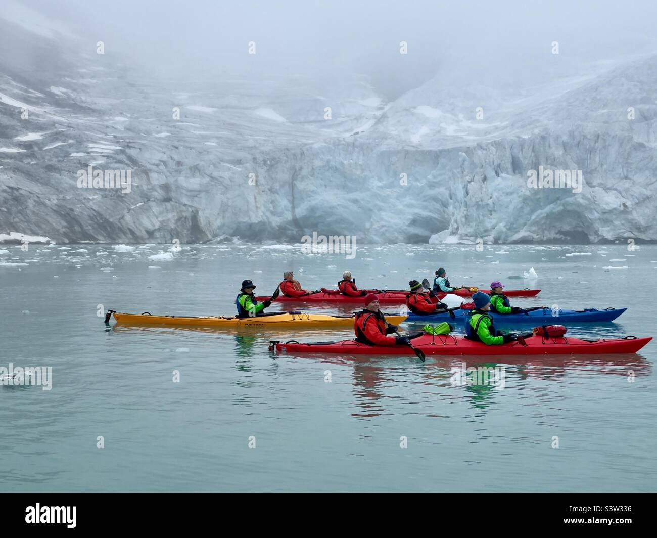 Kayak nella regione di Spitsbergen della Norvegia settentrionale con un ghiacciaio in lontananza Foto Stock