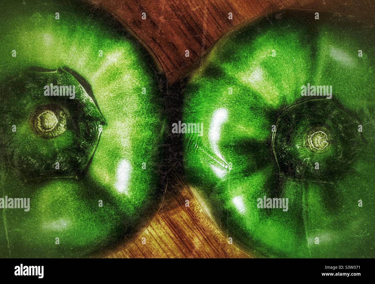 Immagine di una coppia di peperoni verdi su un tavolo di legno con illuminazione drammatica. Effetto grunge aggiunto digitalmente per effetto artistico. Foto Stock