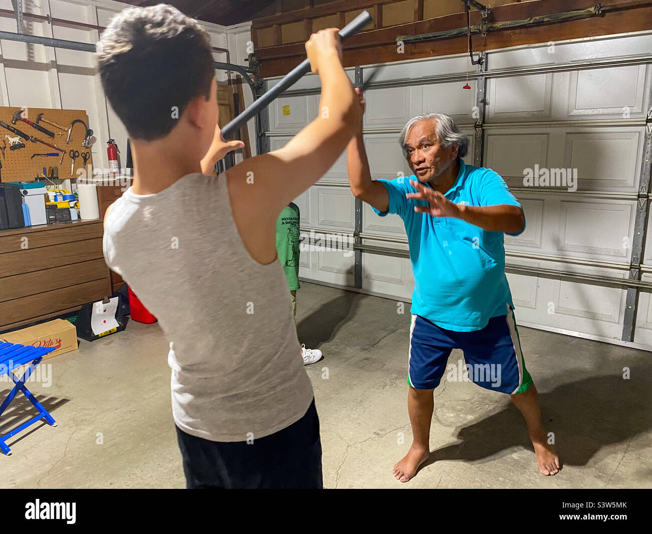 Un ragazzo imparando arnis, un'arte marziale usando i bastoni da è zio. Foto Stock