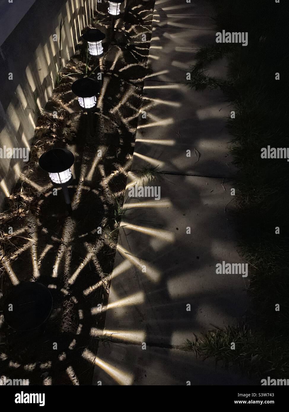 Motivi di luce e ombra dalle lanterne lungo un percorso Foto Stock