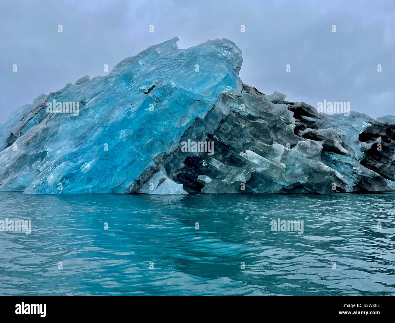 Incredibile iceberg turchese e grigio con colori simili a gemme in un fiordo nella Groenlandia orientale Foto Stock