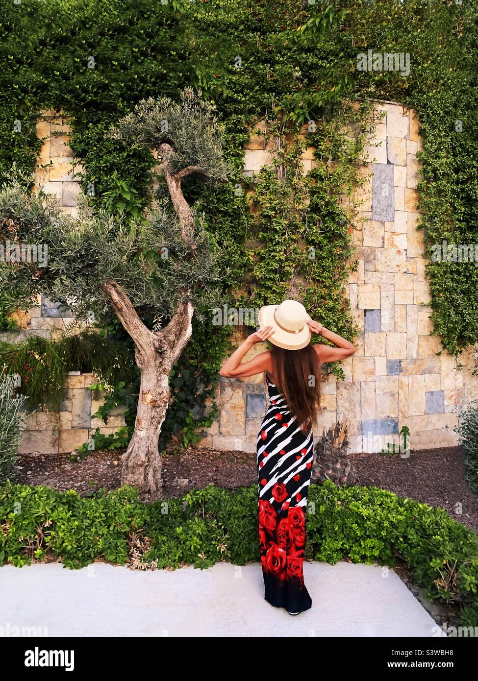 Giovane donna con lunghi capelli in piedi nel verde giardino estivo - Immagine stock catturata con smartphone