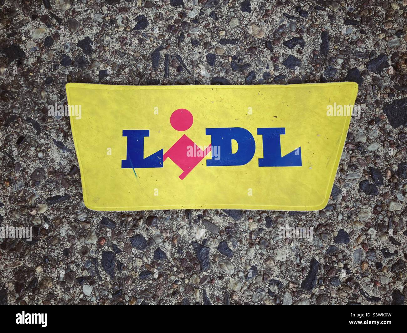 Un pezzo di plastica con il nome di marchio Lidl su di esso che giu' sull'asfalto - Immagine stock catturata con smartphone