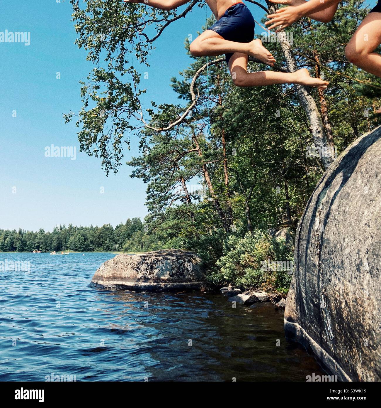 Due ragazzi che saltano da una scogliera ad un lago a Smaland, Svezia Foto Stock