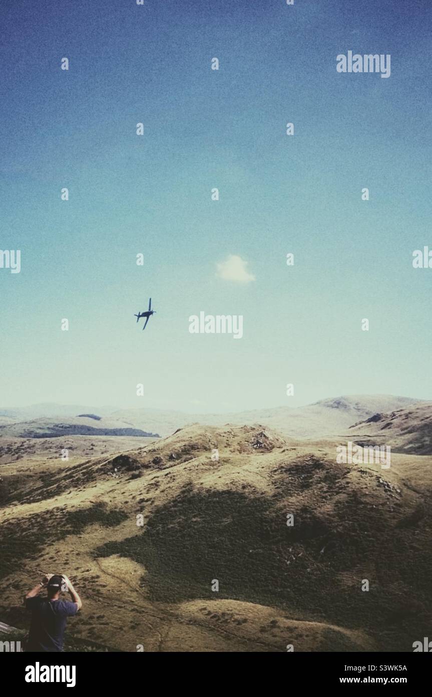 Un uomo che filma un aereo che sorvola le valli di Mach Loop sul suo cellulare. Quest'area è utilizzata come aree di formazione di basso livello per velivoli veloci. Dolgellau, Galles, Regno Unito. Foto Stock