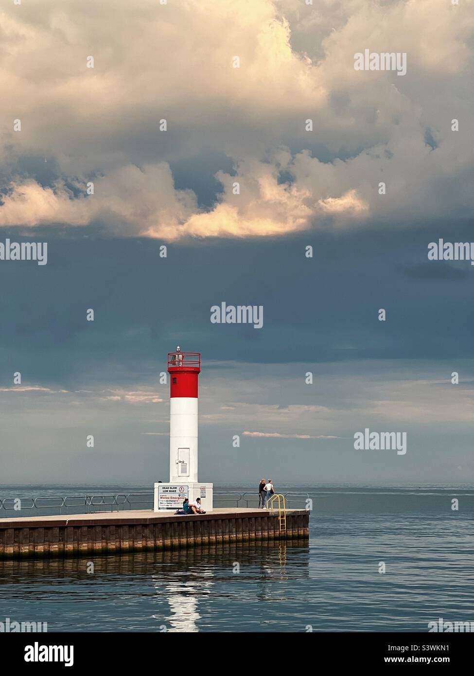 Faro alla fine del molo con cielo tempestoso. Lago Ontario Canada. Agosto 2022 Foto Stock