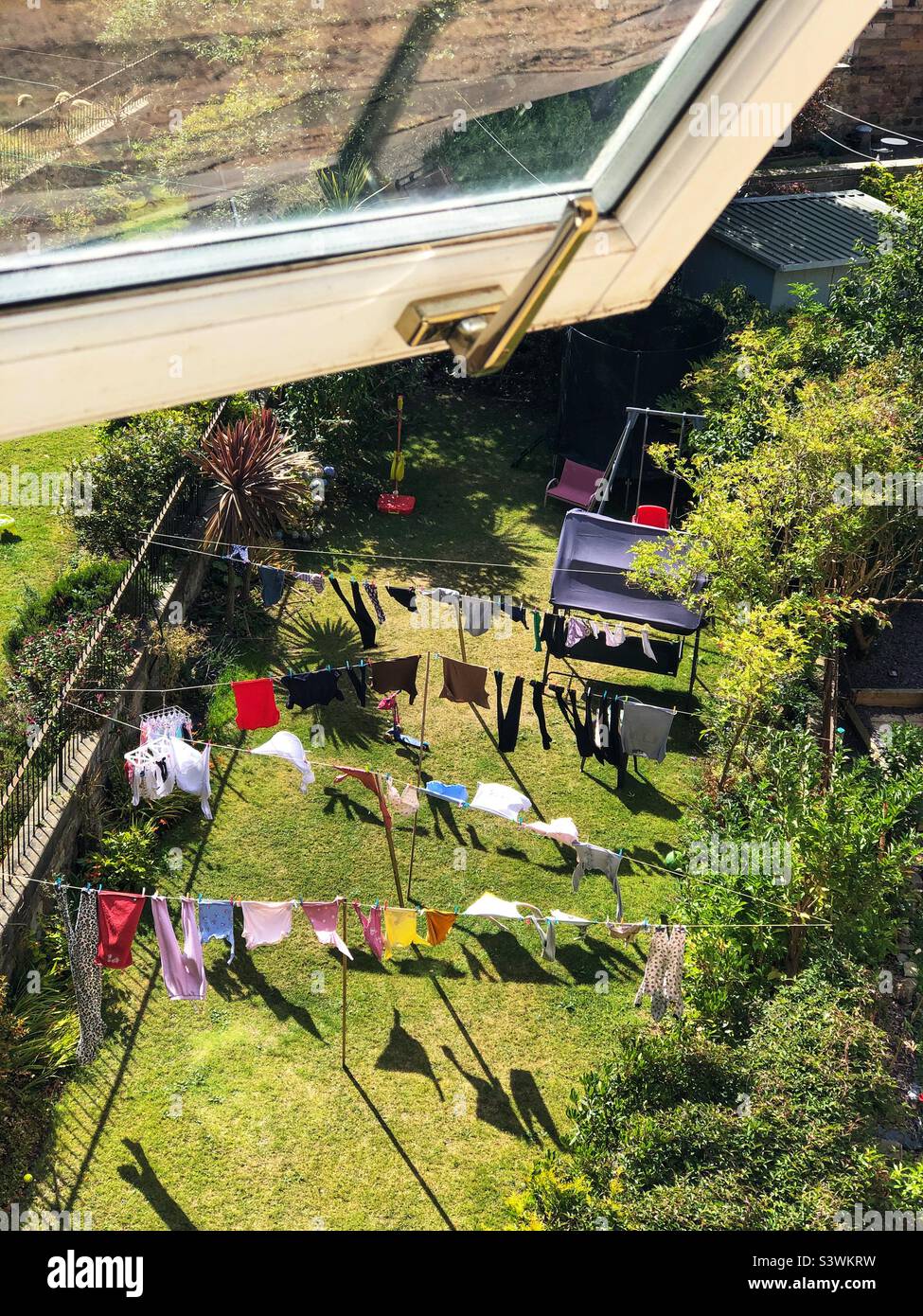 Vestiti appesi per asciugare su una linea di lavaggio in un giardino suburbano posteriore - Immagine stock catturata con smartphone