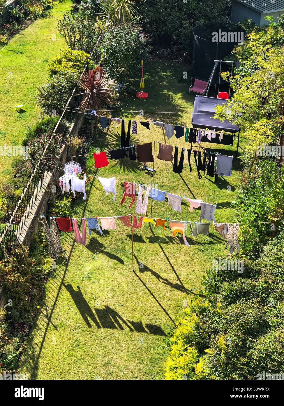 Vestiti appesi per asciugare su una linea di lavaggio in un giardino suburbano posteriore - Immagine stock catturata con smartphone