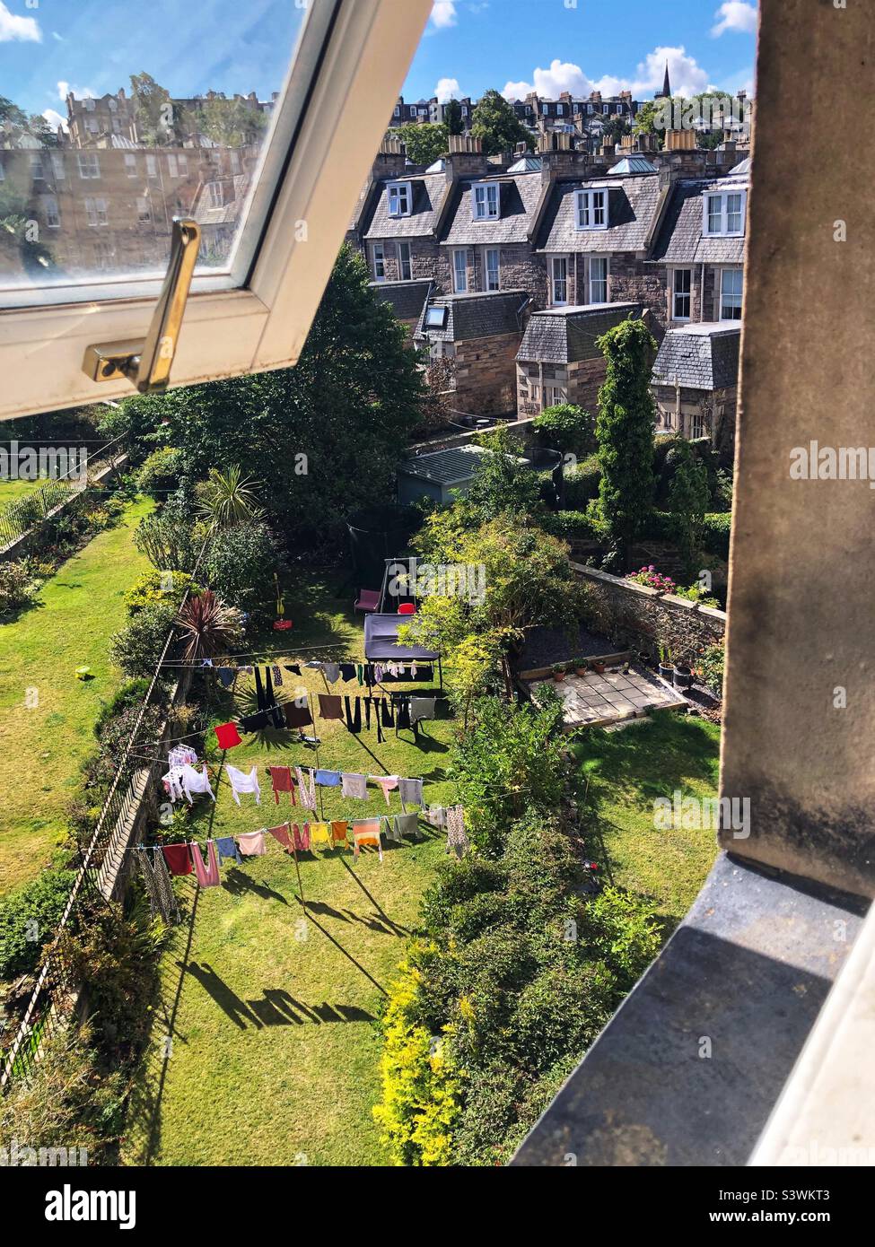 Vestiti appesi per asciugare su una linea di lavaggio in un giardino suburbano posteriore - Immagine stock catturata con smartphone