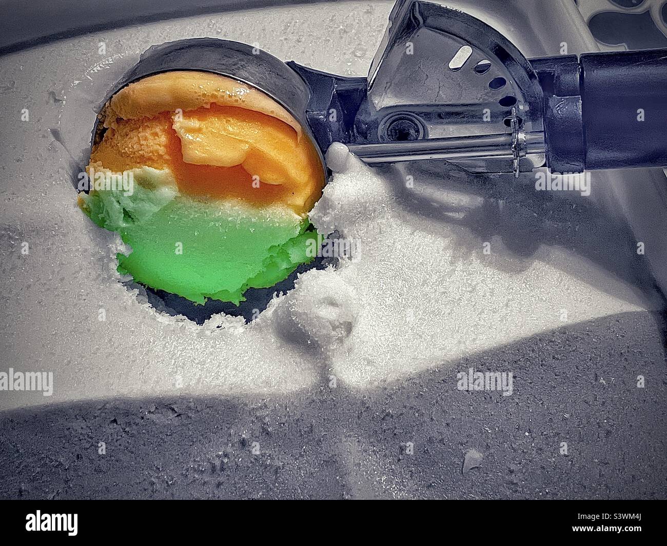 Un'immagine a colori selezionata di una paletta per gelato che raccoglie un po' di gelato sherbet arcobaleno. Foto Stock