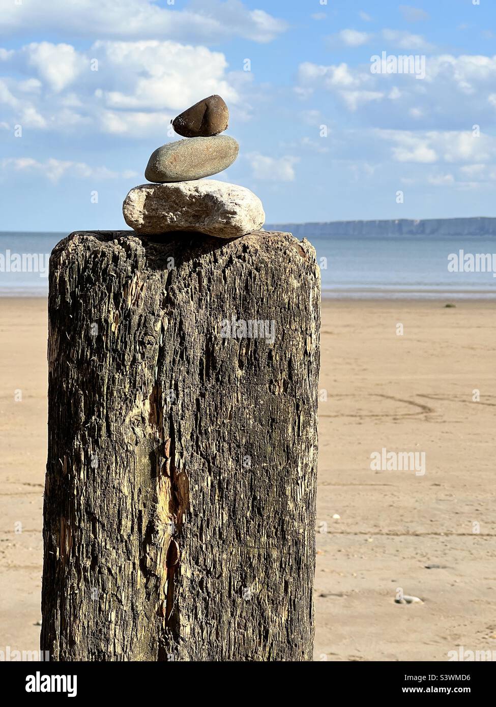 Roccia stack su un palo di legno su una spiaggia - Immagine stock catturata con smartphone