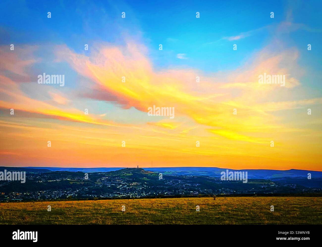 ‘Yorkshire Glow’ un tramonto di colore fuoco mozzafiato in una serata estiva sulla città di Huddersfield. Il bagliore serale illumina Castle Hill e le aree circostanti Foto Stock