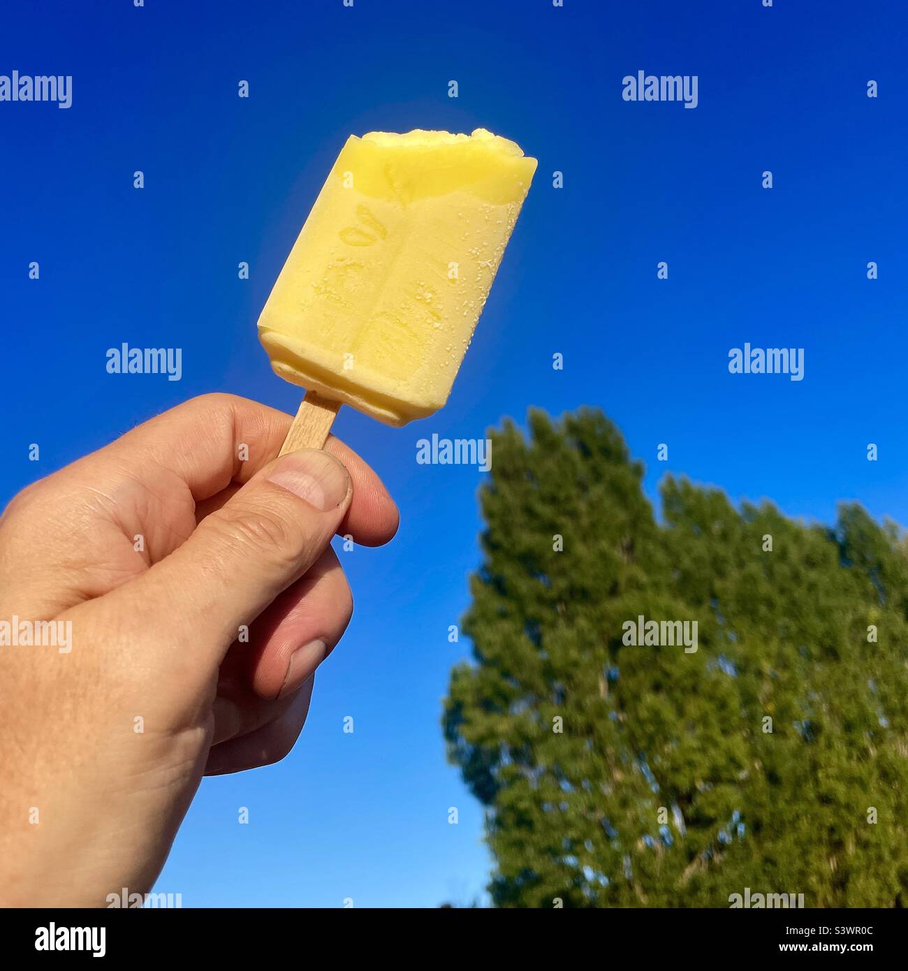 Un ghiaccio giallo lolly contro un cielo blu Foto Stock