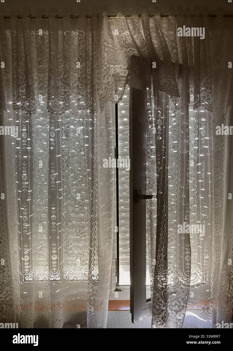 Caldo sole pomeridiano attraverso ciechi quasi chiusi all'esterno finestre aperte a doppi vetri con tende a rete in un villaggio in Spagna - Immagine stock catturata con smartphone Caldo sole pomeridiano attraverso ciechi quasi chiusi all'esterno finestre aperte a doppi vetri con tende a rete in un villaggio in Spagna - Immagine stock catturata con smartphone