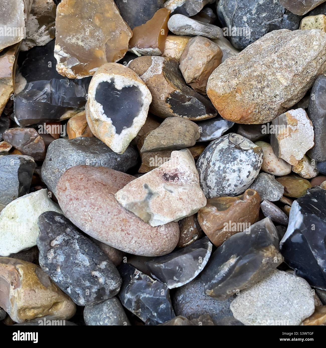 Forma di cuore nero all'interno di pietra aperta spaccata tra la raccolta di pietre e ciottoli Foto Stock