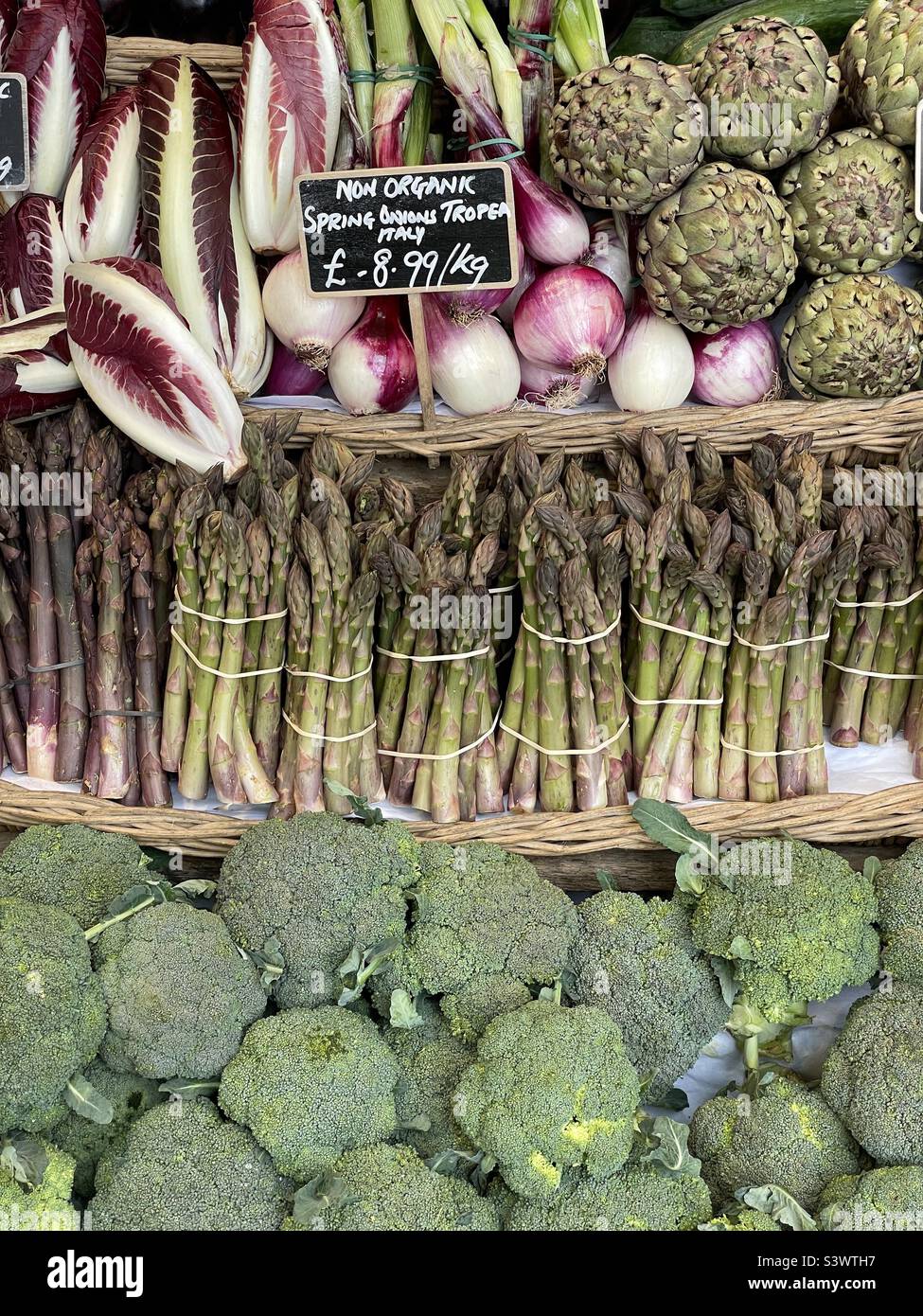 Selezione di verdure esposte in azienda agricola tra cui broccoli, asparagi, cipolle rosse e radicchio Foto Stock