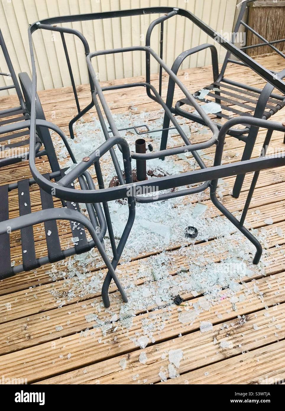 Ops! Il tavolo da giardino in vetro frantumato subito dopo il vento ha fatto esplodere il ombrellone del giardino dalla sua base e giù sul tavolo. Foto Stock