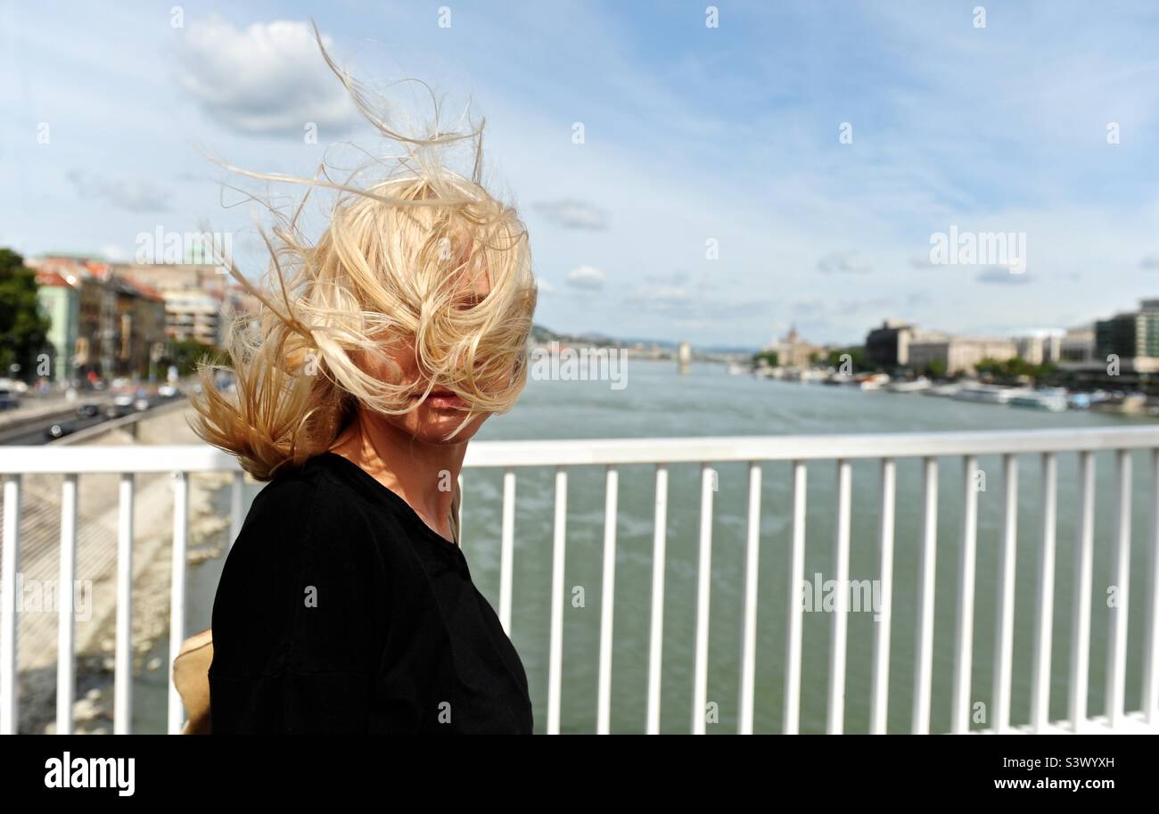 Donna sul ponte con i capelli biondi ventosi Foto Stock