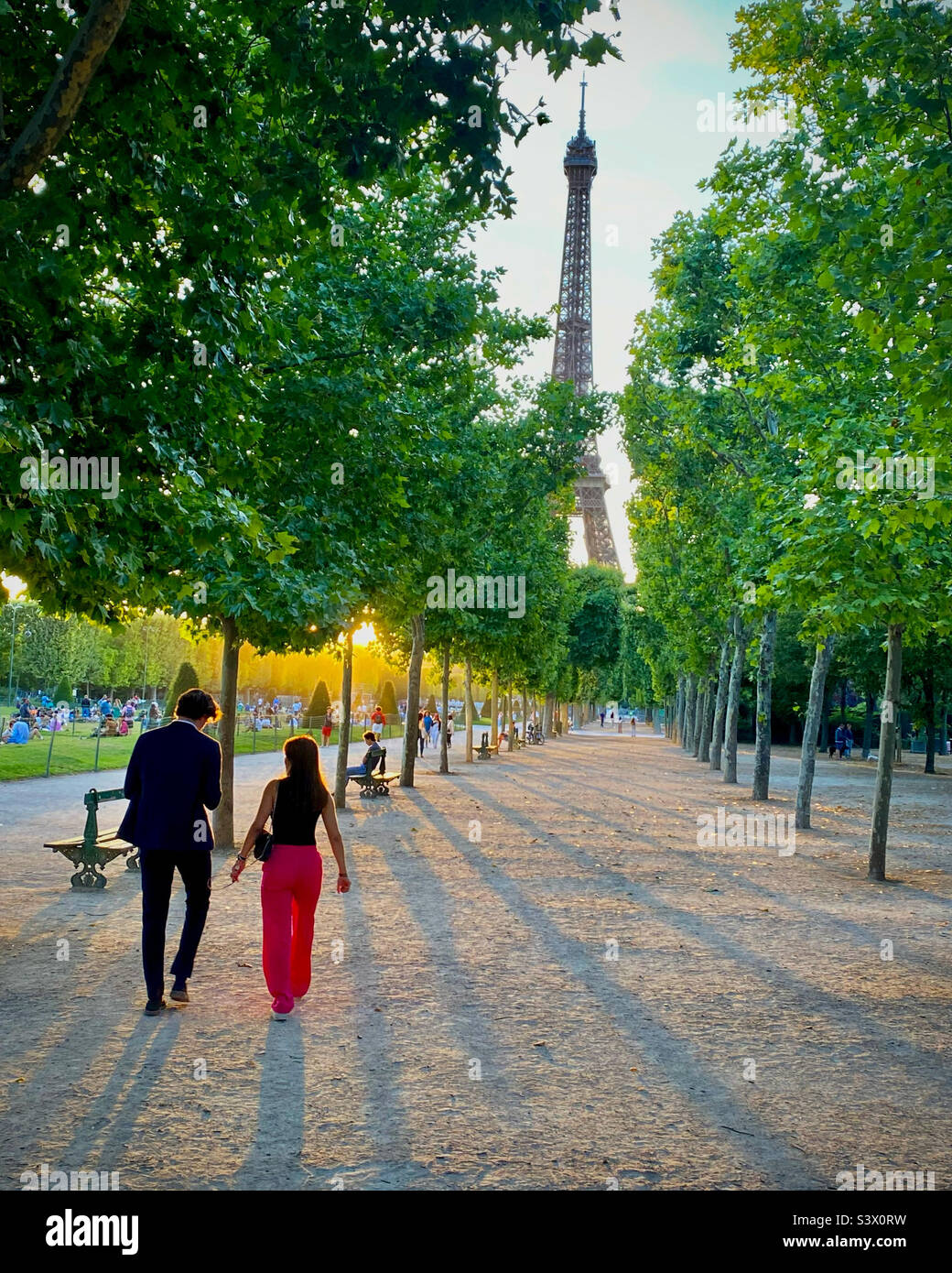 Una giovane coppia che cammina verso la Torre Eiffel a Parigi in un romantico tramonto d'oro Foto Stock