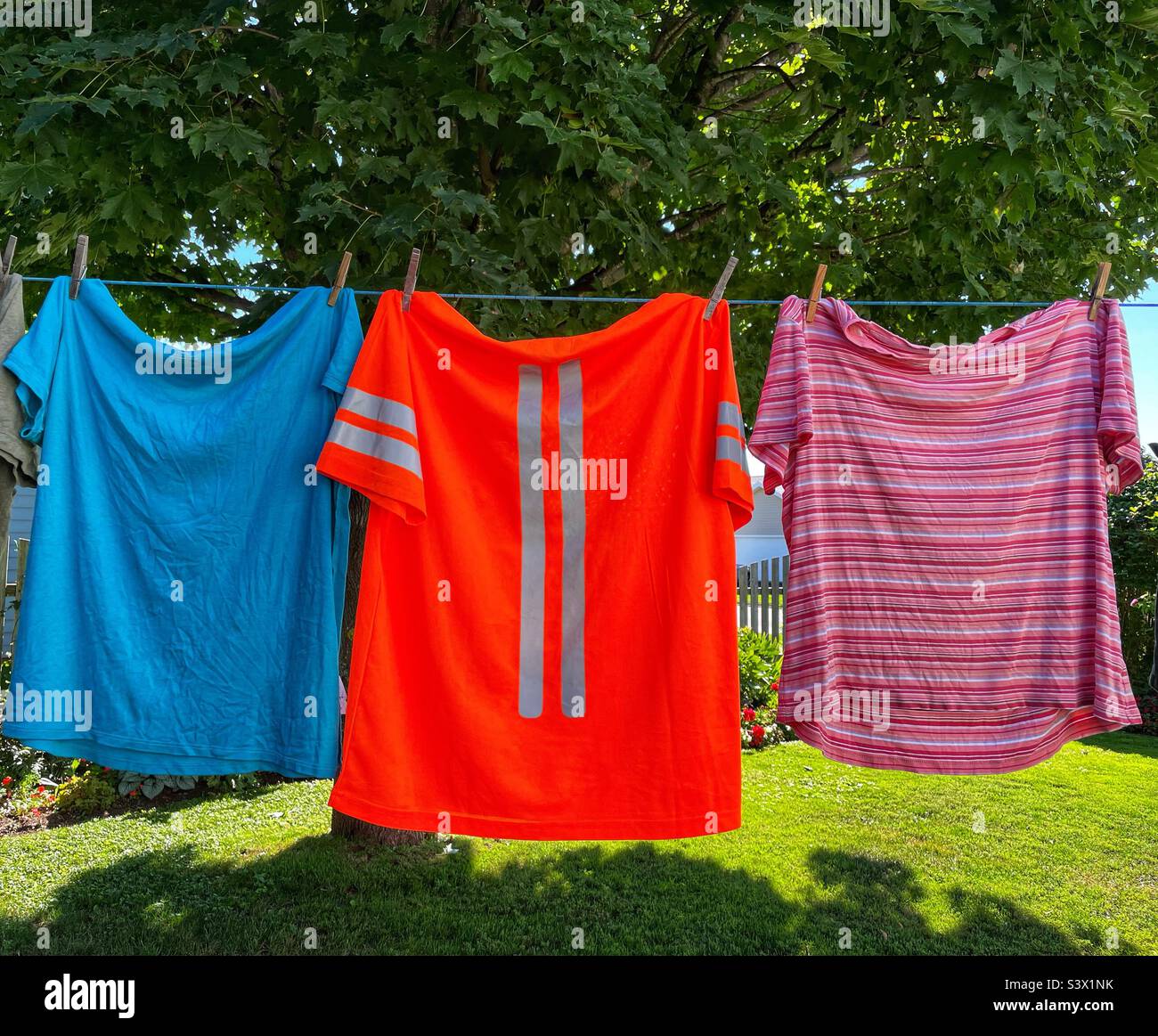 T-shirt e una maglietta di sicurezza arancione con barre riflettenti, tutte appese sul vestito. Foto Stock